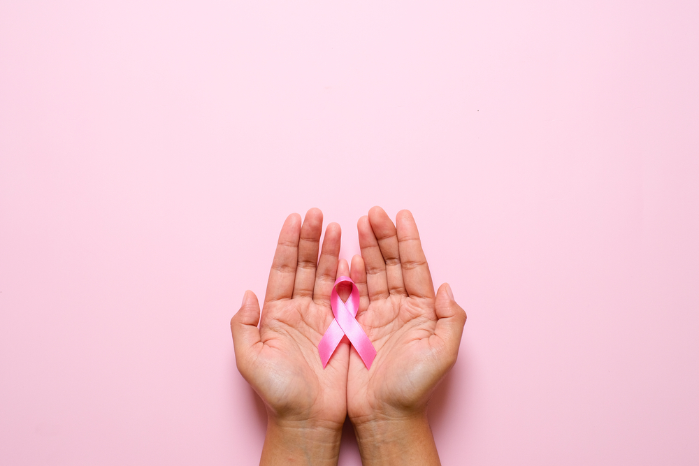 Woman,Hands,Holding,Pink,Ribbon,Over,Pink,Background,,Breast,Cancer